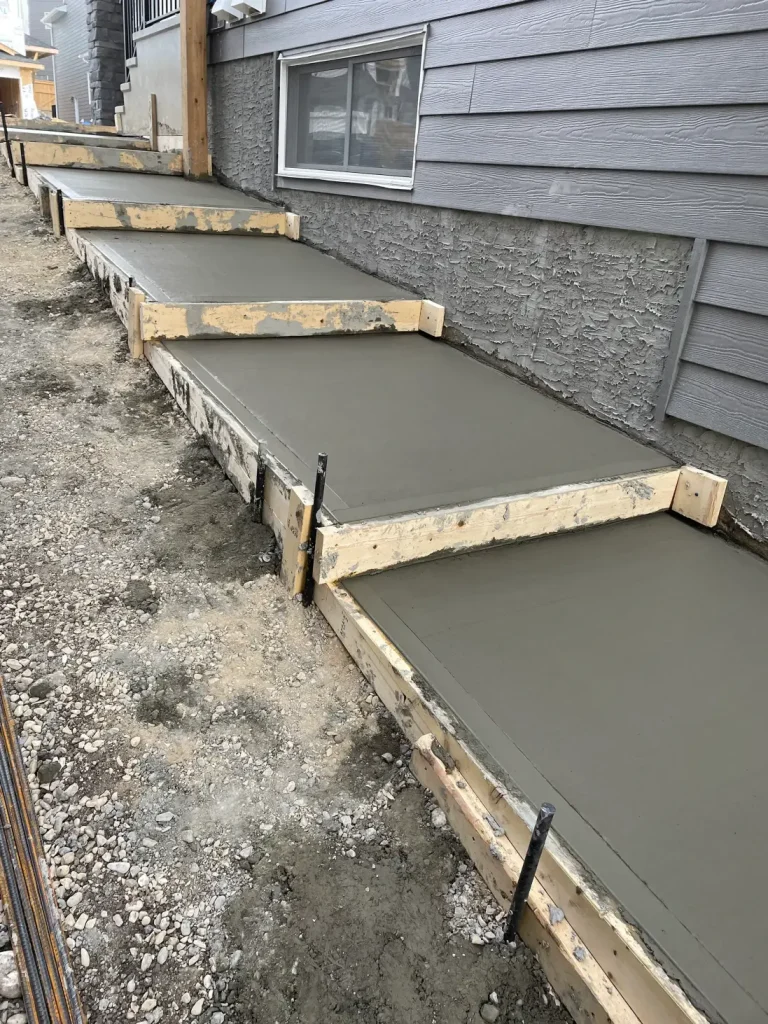 Contractors pouring cement for Concrete Sidewalks Calgary at a residential home.