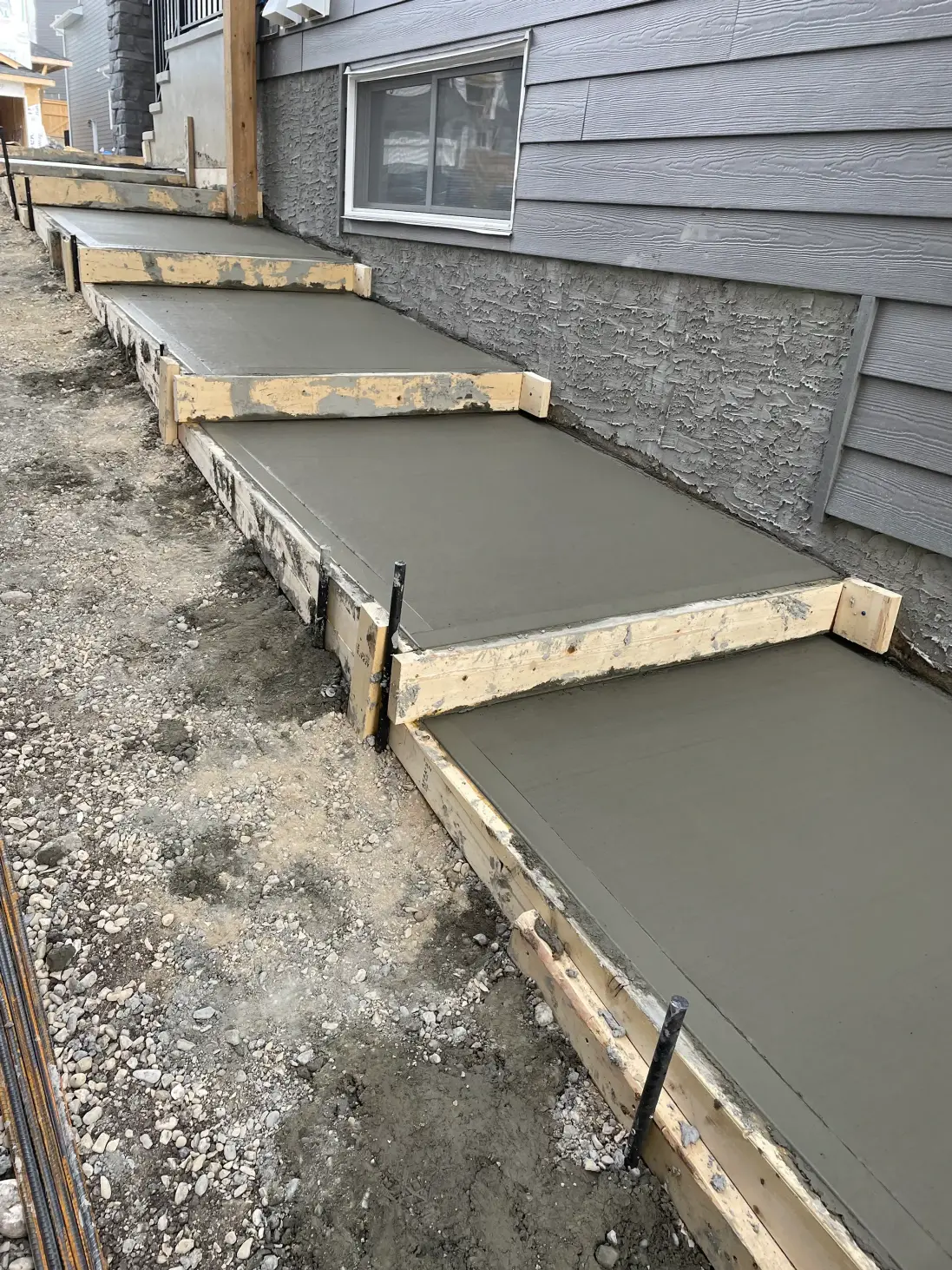 Building contractors Calgary install freshly poured concrete steps within wooden forms