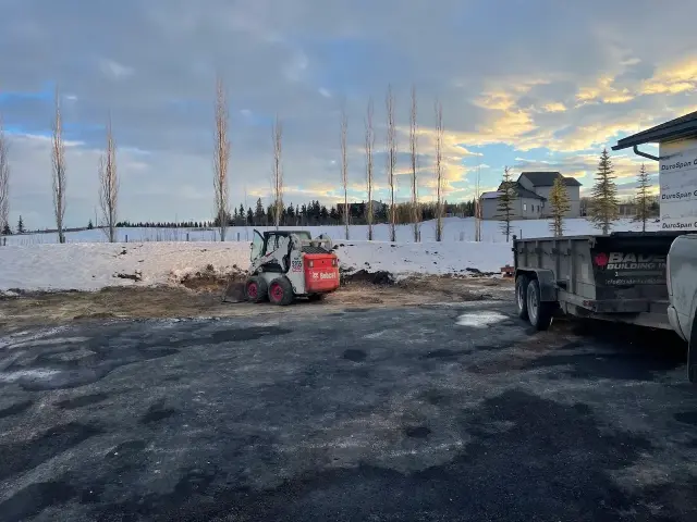 Building contractors Calgary navigate a snowy construction site with a small vehicle
