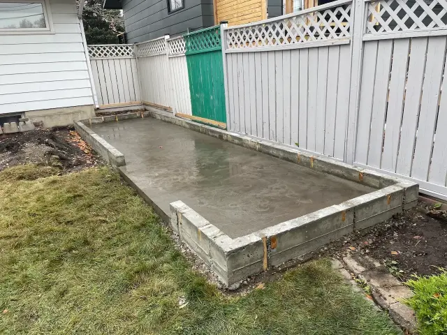 Building contractors Calgary preparing a concrete slab in a backyard with wooden framing