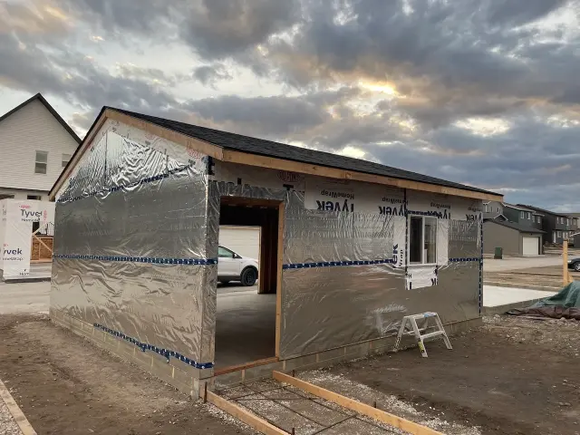 Building contractors Calgary work on a partially constructed building wrapped in reflective insulation