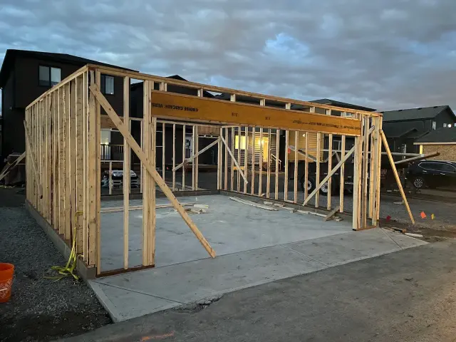 Wooden garage framing in progress on concrete pad