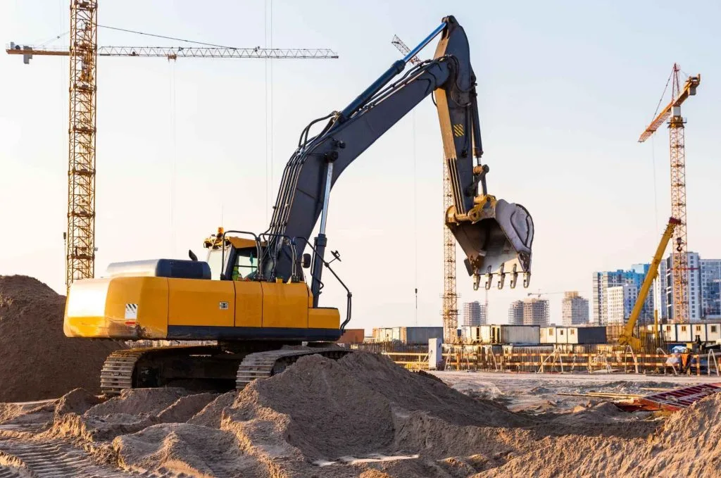 Demolition services Calgary utilize a yellow excavator to dig into sand at a construction site