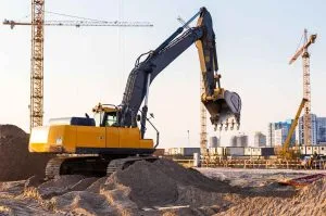 Demolition services Calgary utilize a yellow excavator to dig into sand at a construction site