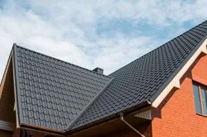 Roofing Calgary features two sloped roofs with dark shingles under a cloudy blue sky
